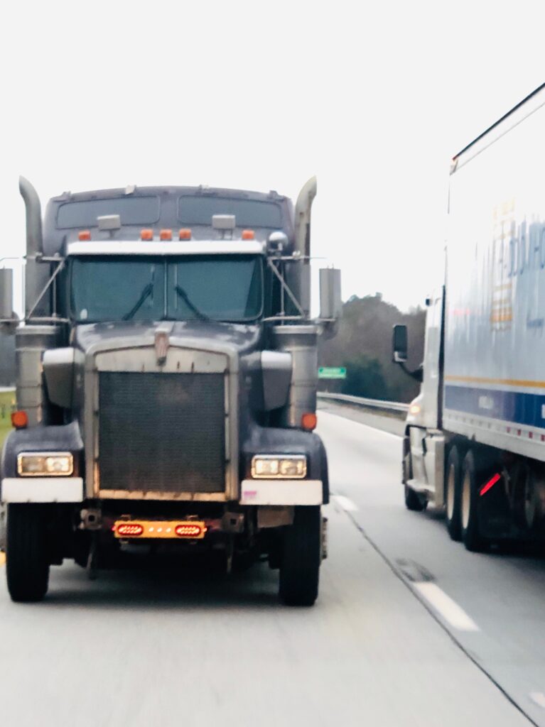 Two truck beside each other, the truck on the left is being towed.